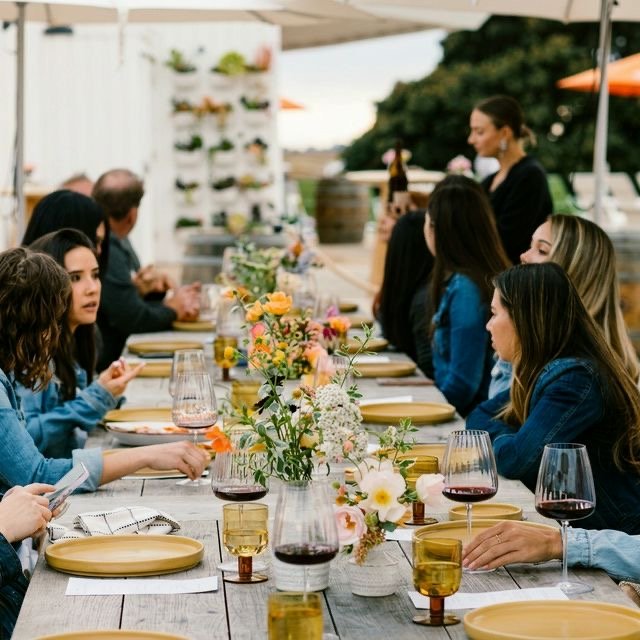 Friends sharing a meal around a flower-filled table